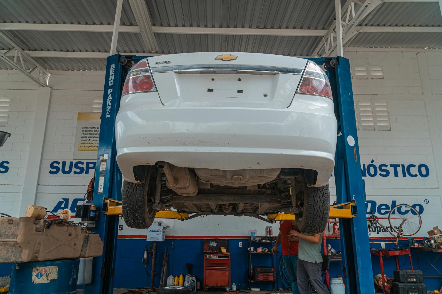 Biały Chevrolet uniesiony na podnośniku w warsztacie samochodowym