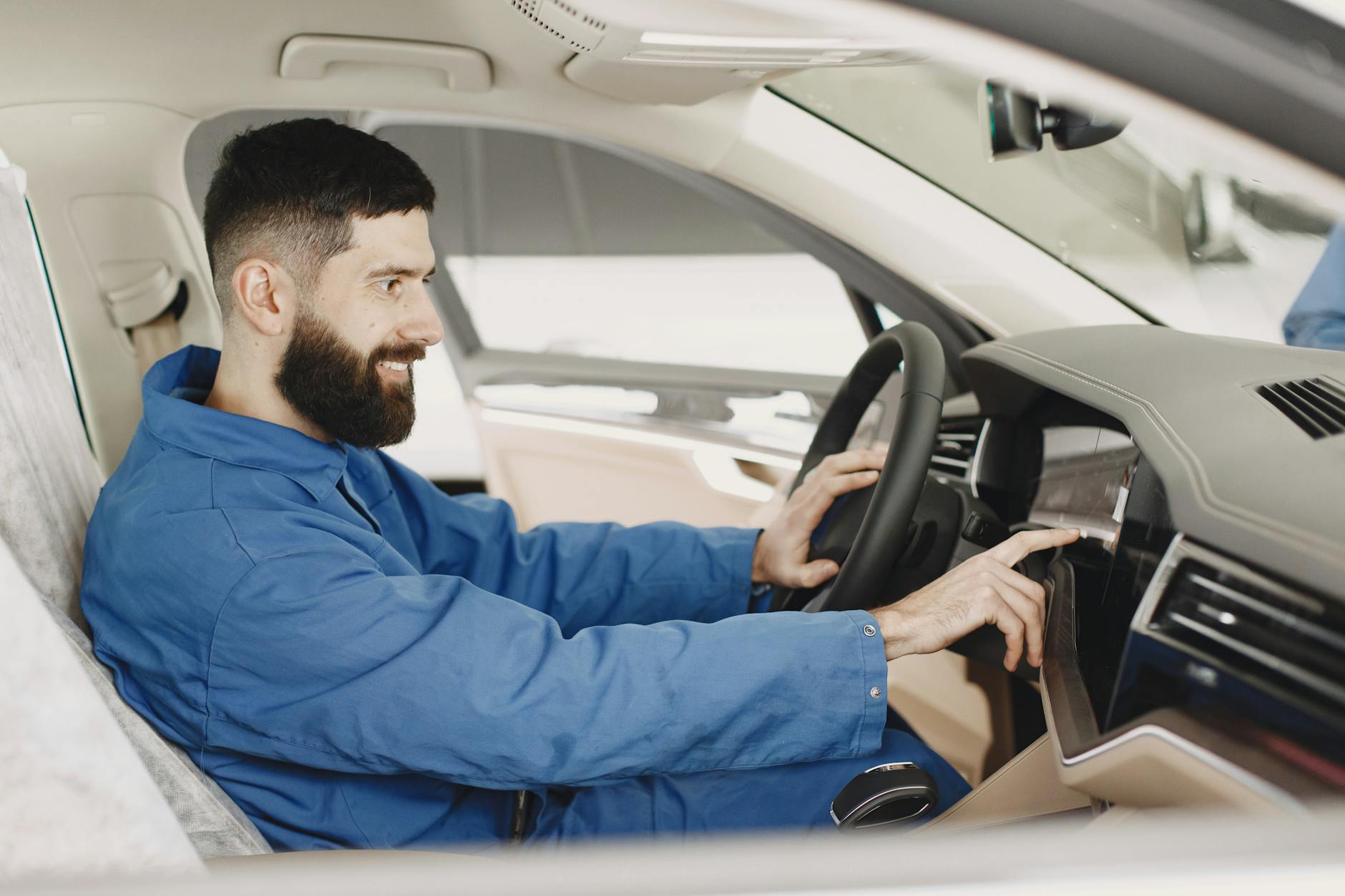 Mechanik w niebieskim kombinezonie sprawdza deskę rozdzielczą auta
