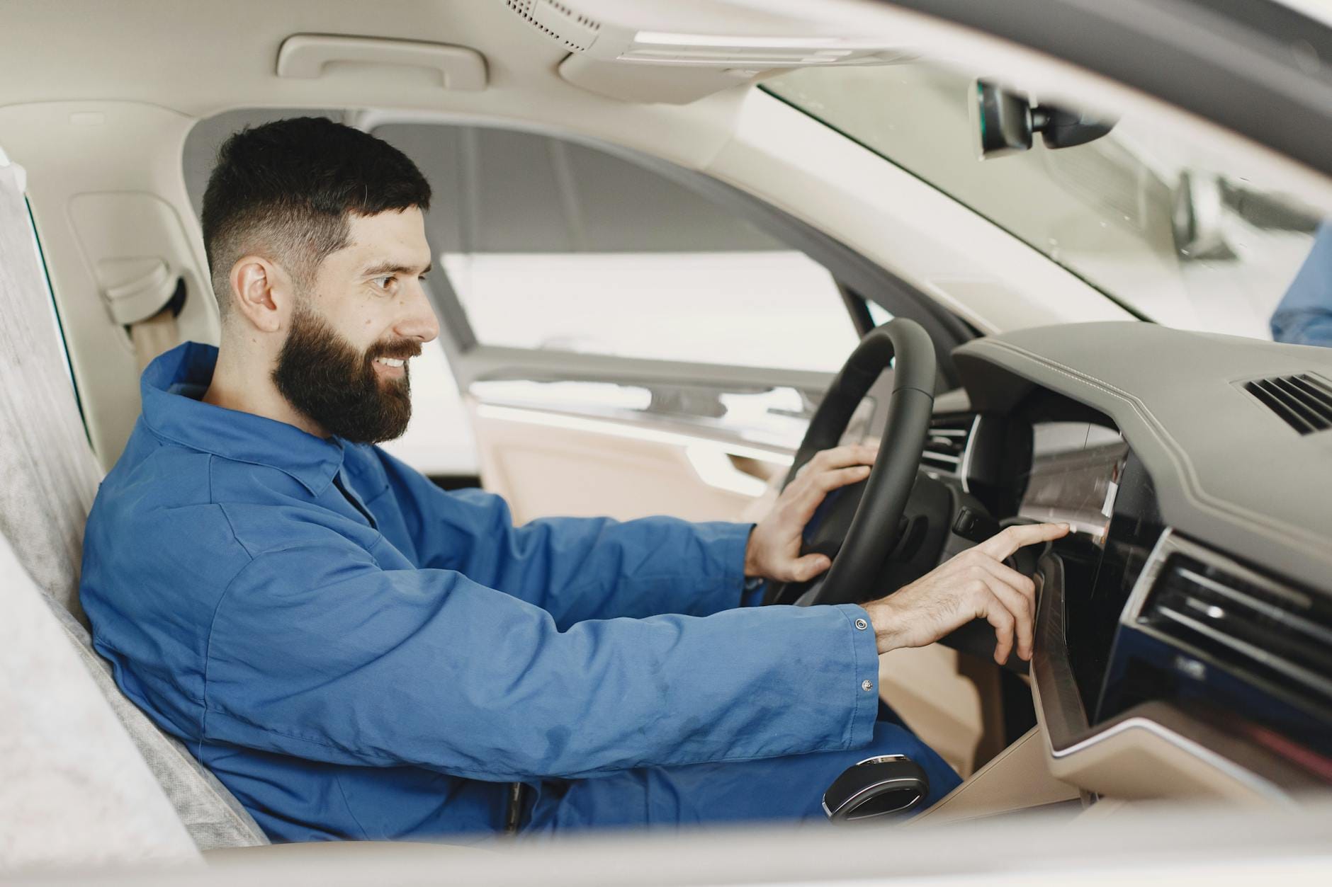 Mechanik w niebieskim kombinezonie sprawdza deskę rozdzielczą auta