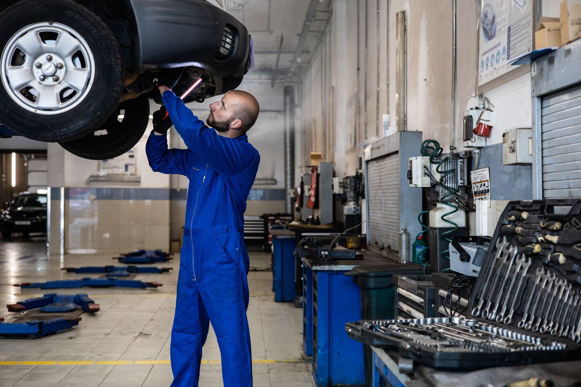 Mechanik ogląda od spodu podniesiony samochód w warsztacie
