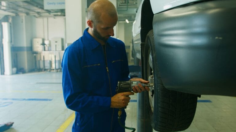 Mechanik w niebieskim kombinezonie serwisuje samoch